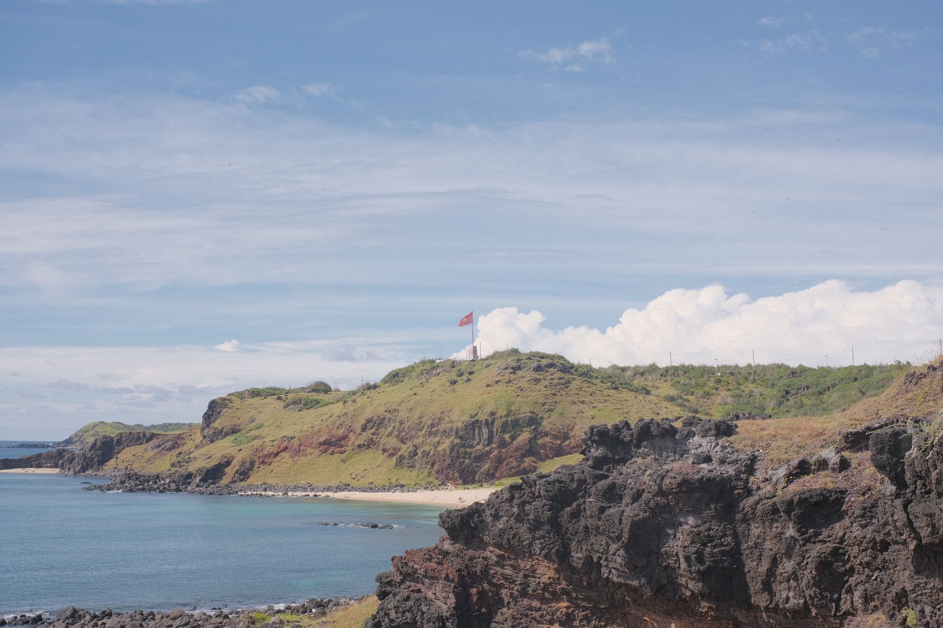 Lighthouse on the rocky coastline of Phú Quý Island, Vietnam, overlooking the ocean.