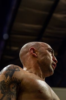Close-up of a focused bald martial artist indoors, showcasing strength and determination.