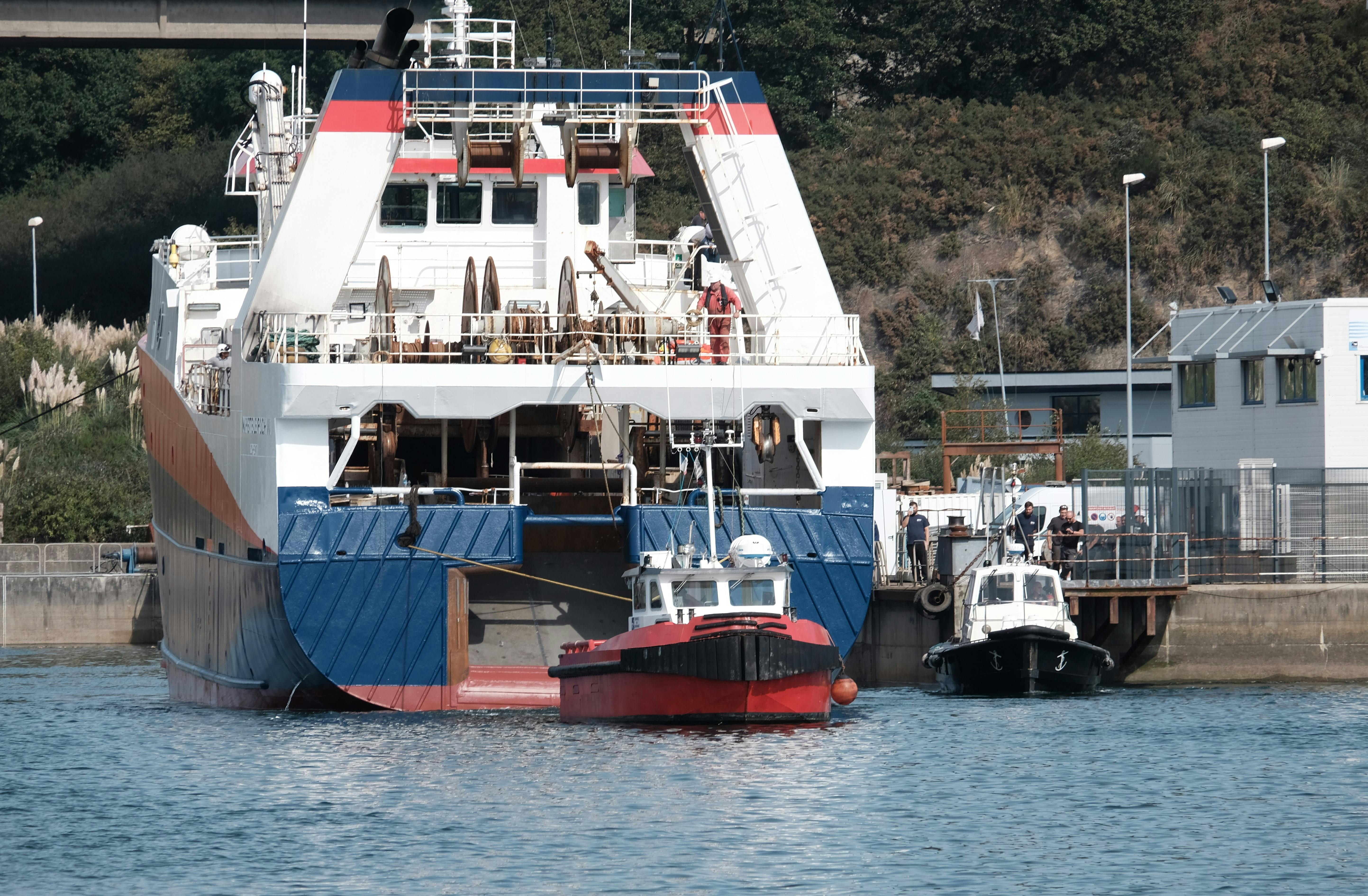 Tugboats maneuver a large ferry at a busy harbor, offering a glimpse into marine transportation.