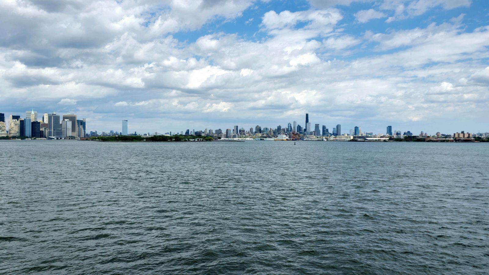 Panoramic view of New York City skyline from the harbor, capturing iconic skyscrapers.