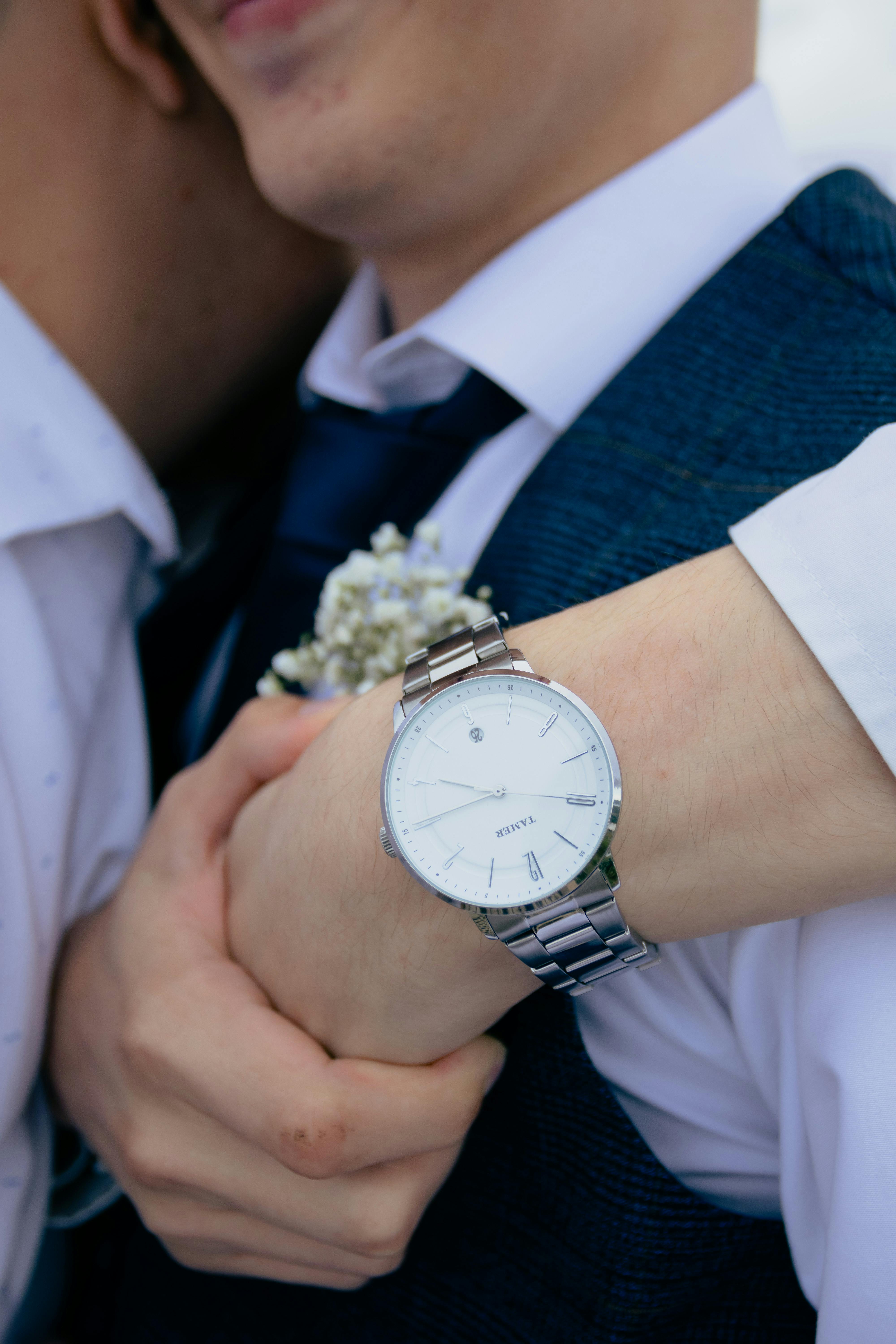A couple embraces showing an elegant watch and attire, conveying love and fashion.