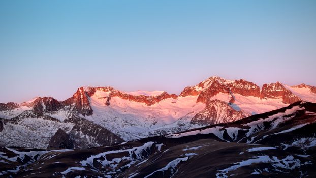 Beautiful view of the sunlit Pyrenees mountains at dawn with vibrant pink hues.