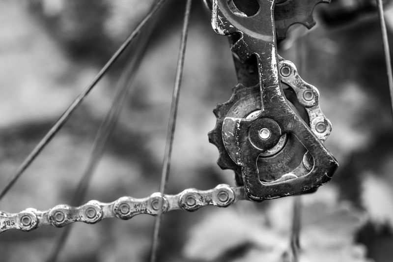 A detailed black and white shot of a bicycle gear and chain mechanism.