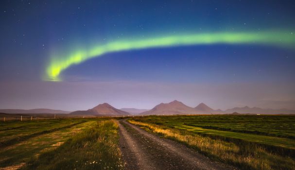 Mesmerizing view of the aurora borealis illuminating the Icelandic night sky over a rural landscape.