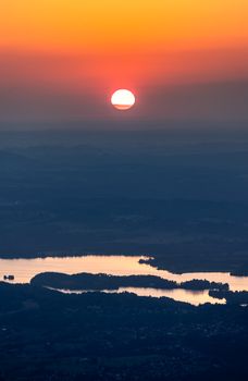 A breathtaking aerial view of a sunset over a calm lake with a vibrant orange sky.