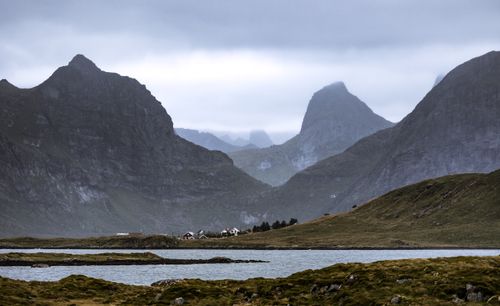 Free Scenic view of Lofoten fjord surrounded by dramatic mountains and houses under a cloudy sky. Stock Photo