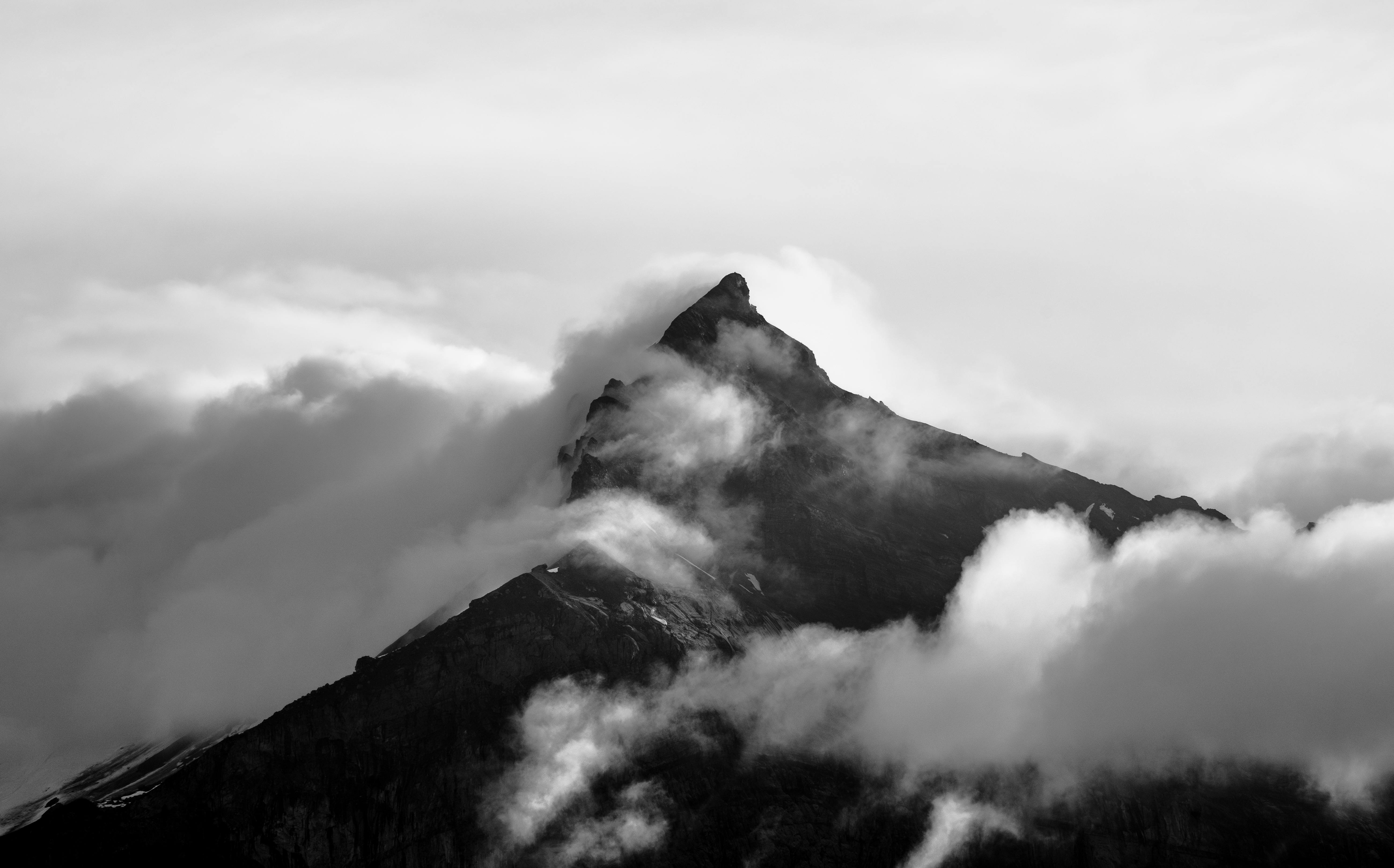 Majestic mountain peak emerging through clouds, capturing a serene natural drama in black and white.