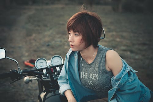 オートバイに寄りかかっている女性の写真