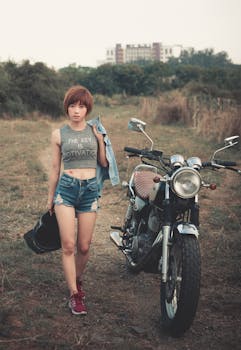 在农村的背景下，一位时尚女性身着休闲装，站在摩托车旁