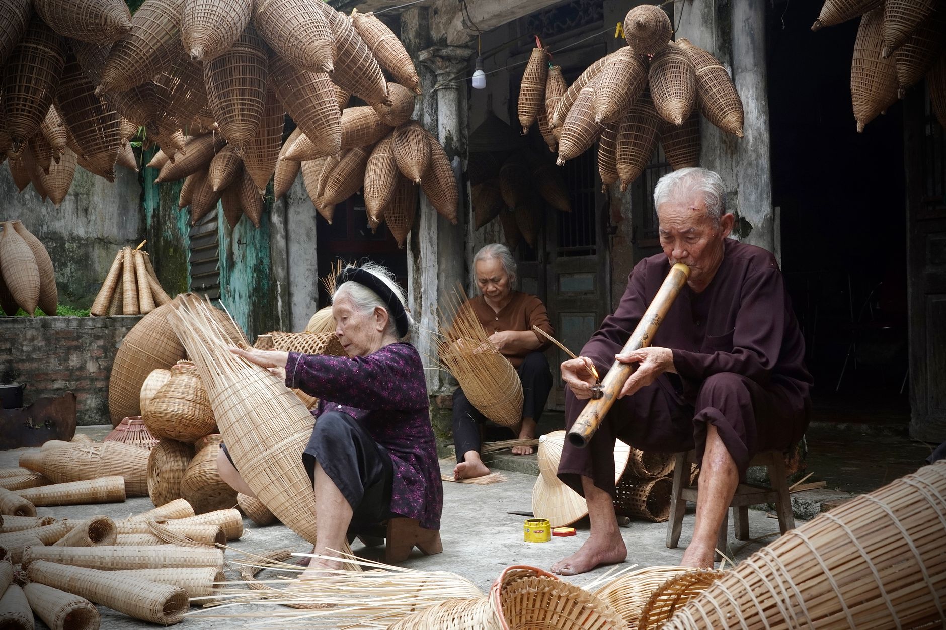 Elderly artisans crafting traditional bamboo baskets in Hanoi, capturing Vietnam's rich cultural heritage.