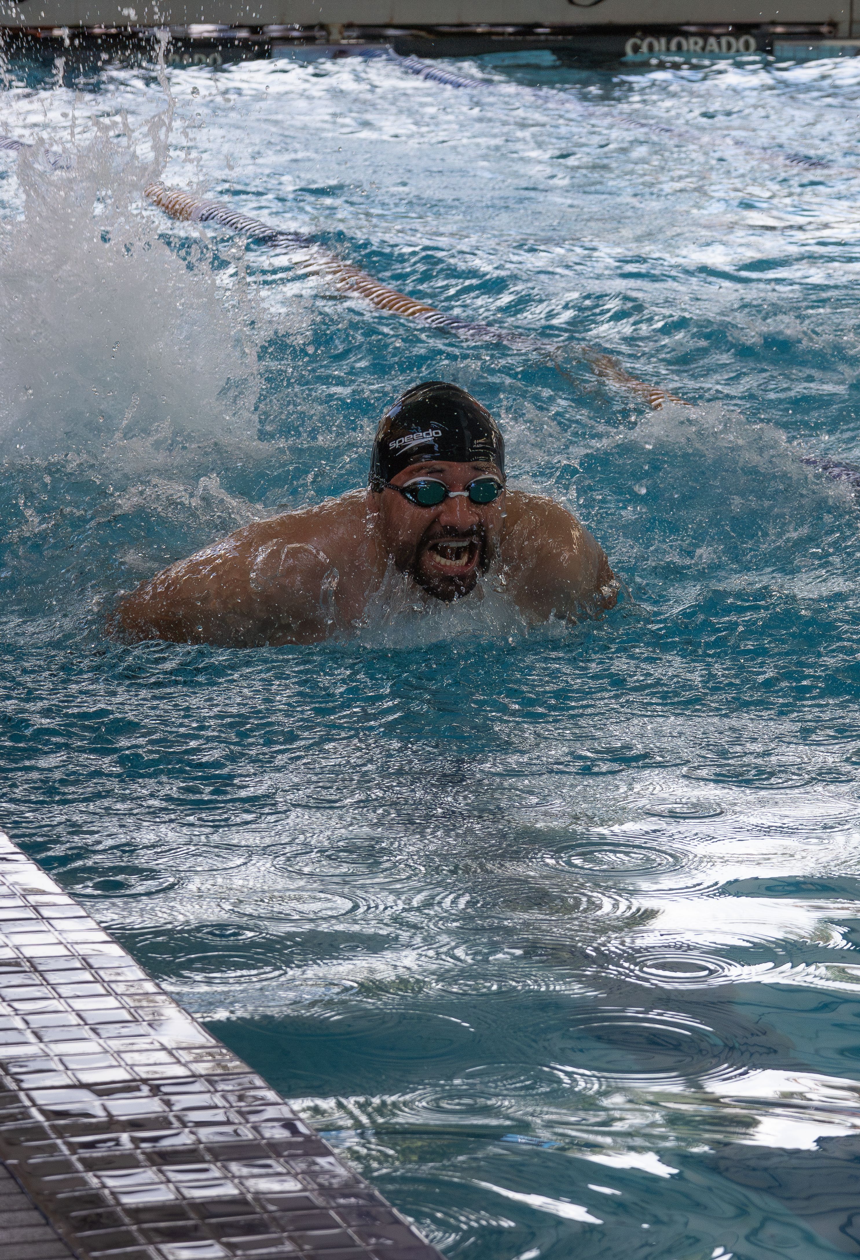 Swimmer competing in butterfly stroke at an indoor pool, San Luis Potosí, Mexico.