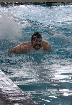 Swimmer competing in butterfly stroke at an indoor pool, San Luis Potosí, Mexico.