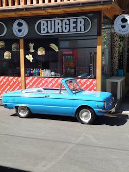 Retro blue convertible car in front of a burger cafe on a sunny day.