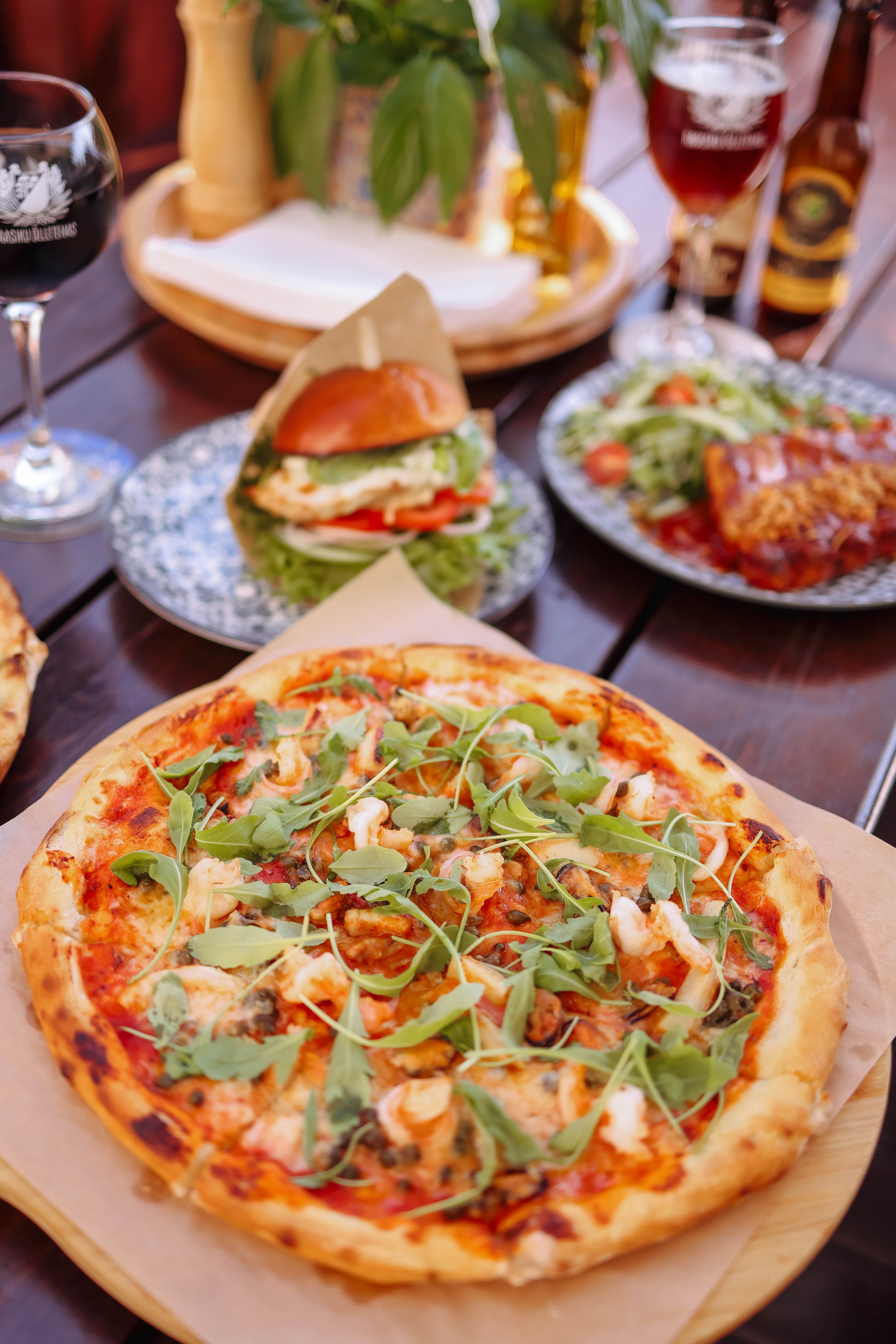 A mouthwatering rustic pizza topped with fresh arugula and tomatoes in an appetizing indoor setting.