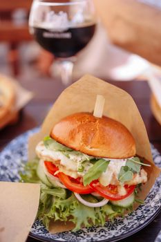 Tasty chicken burger with fresh lettuce and tomato on a rustic plate, perfect for lunch.
