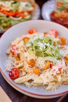 Delicious pasta with cherry tomatoes, arugula, and Parmesan cheese.