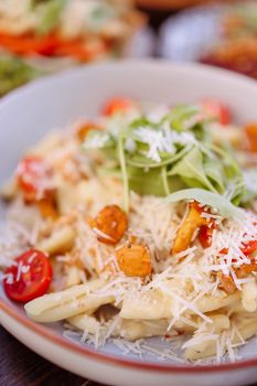 Delicious creamy pasta topped with cherry tomatoes, arugula, and shredded cheese.
