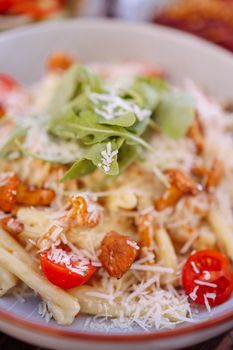Savor this vibrant pasta dish topped with cherry tomatoes, arugula, chanterelle mushrooms, and parmesan cheese.