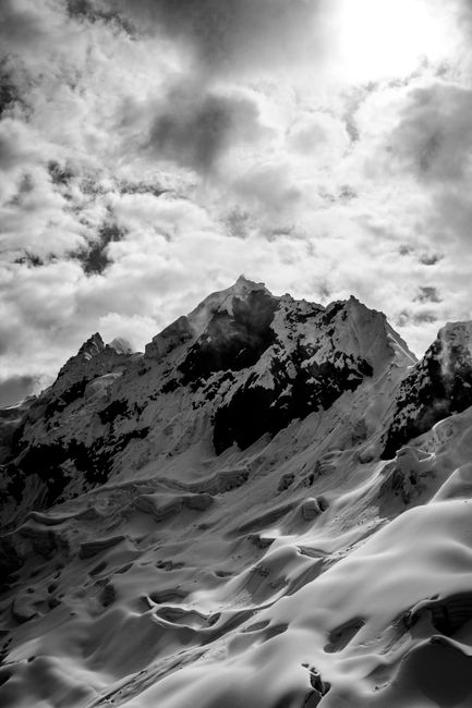 Breathtaking black and white shot of snow-capped mountain under dramatic sky.