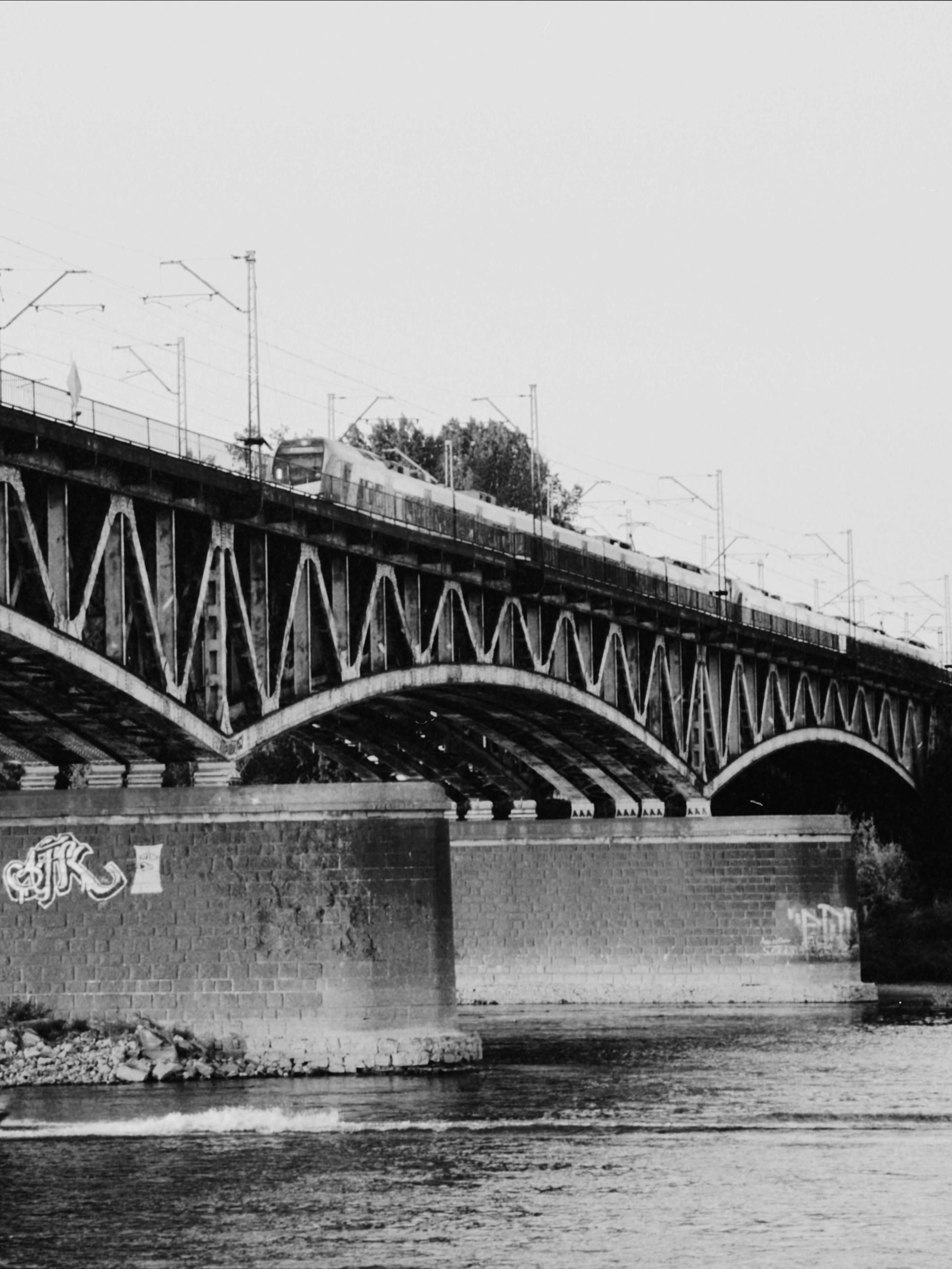 a black and white photo of a bridge over water