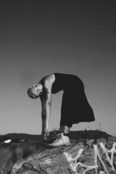 Black and white photo of a woman doing yoga on a rock. Artistic and serene mood.