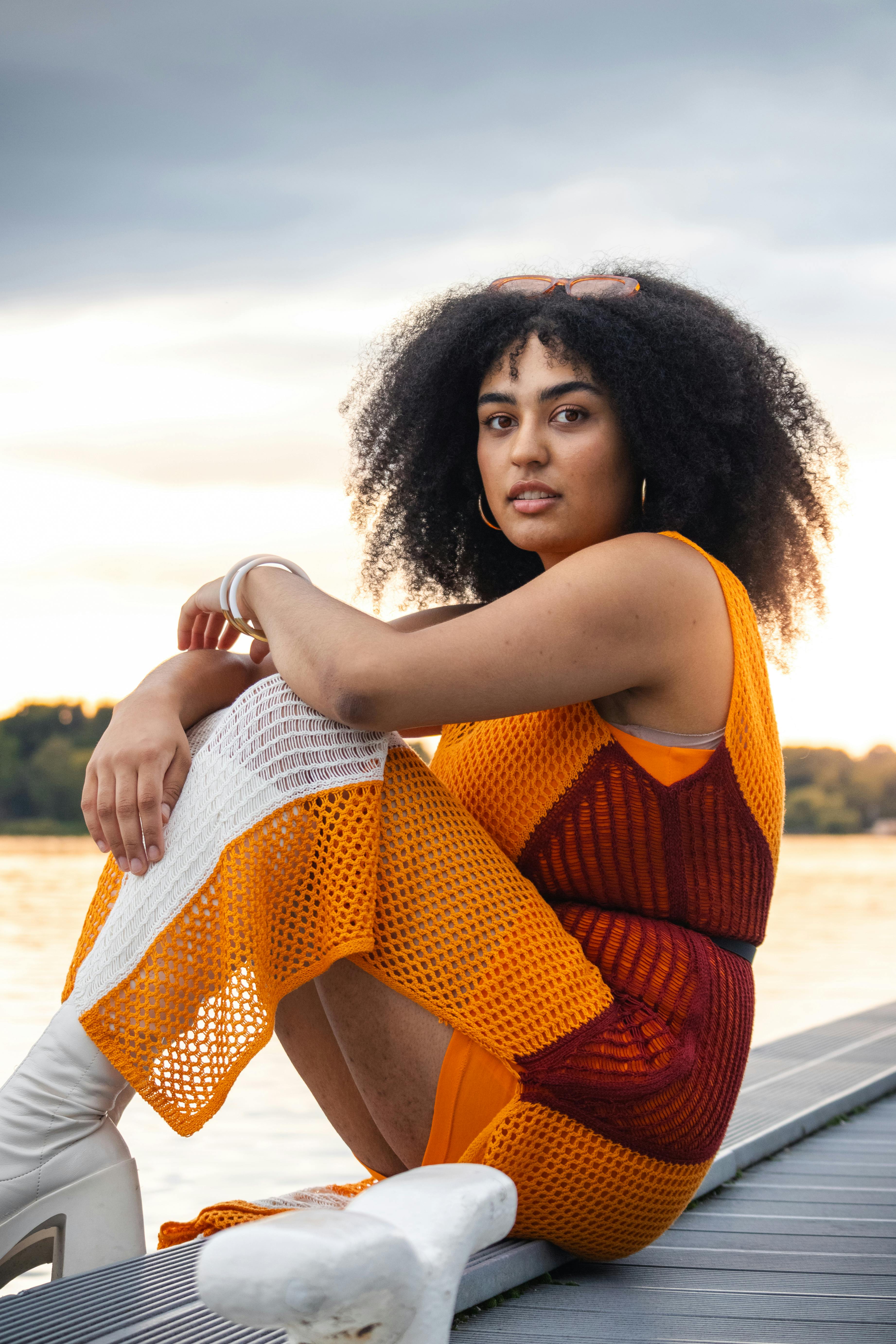 a woman in an orange dress sitting on a dock