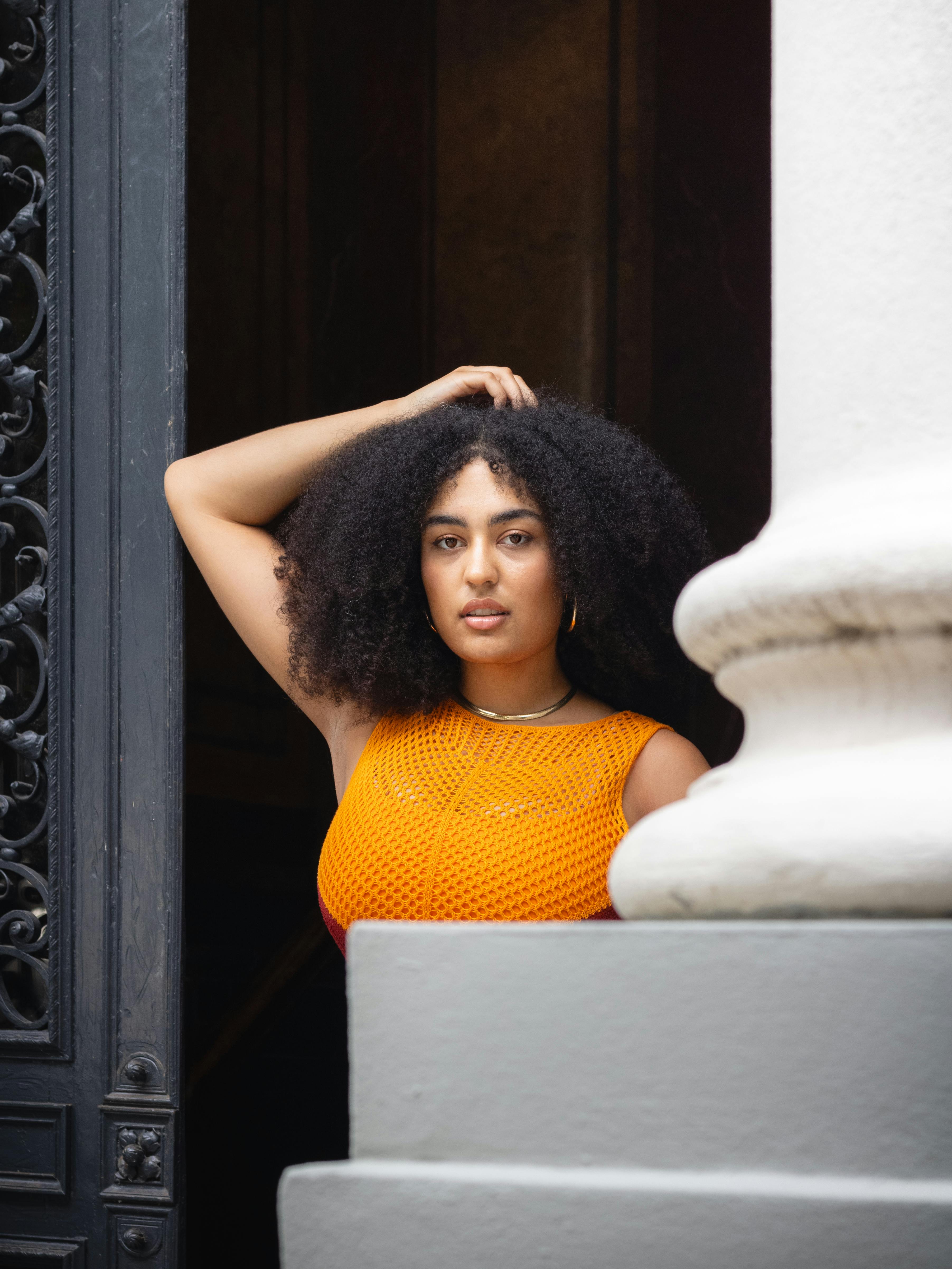 a woman with an afro wearing an orange top