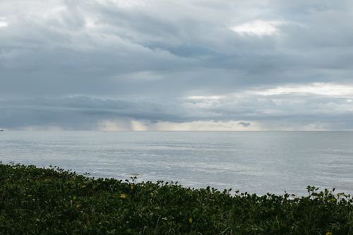 Free A serene coastal landscape with cloudy skies over a calm ocean, evoking a peaceful mood. Stock Photo