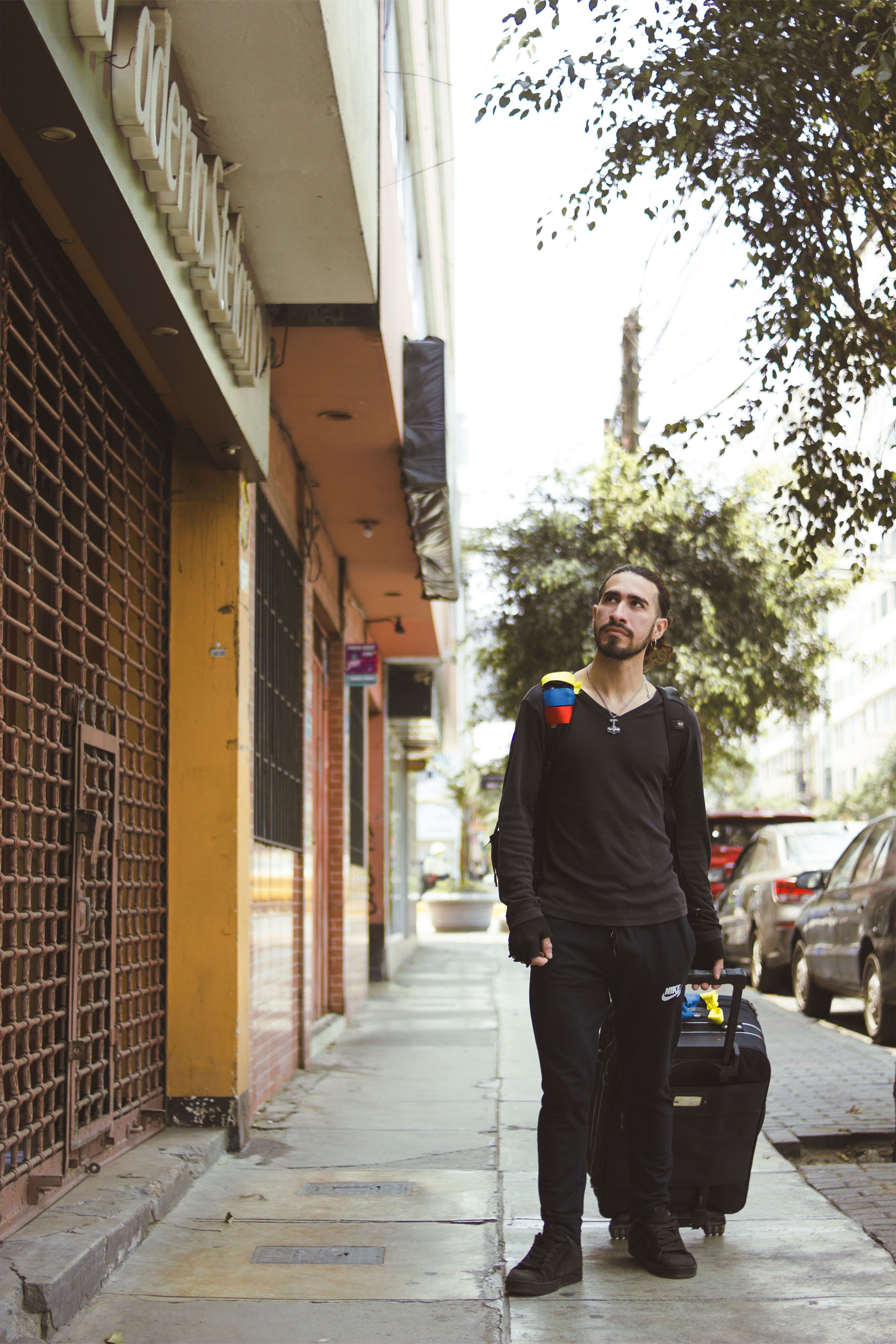 A man strolls along a city street in Lima, Peru, with luggage. Urban travel scene.