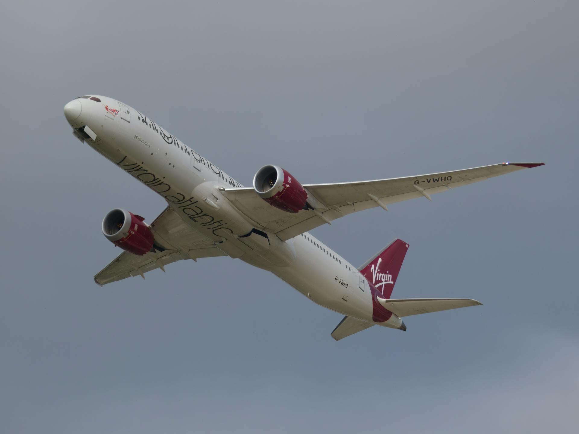 Close-up of a Virgin Atlantic airplane soaring in the cloudy sky, showcasing its design.