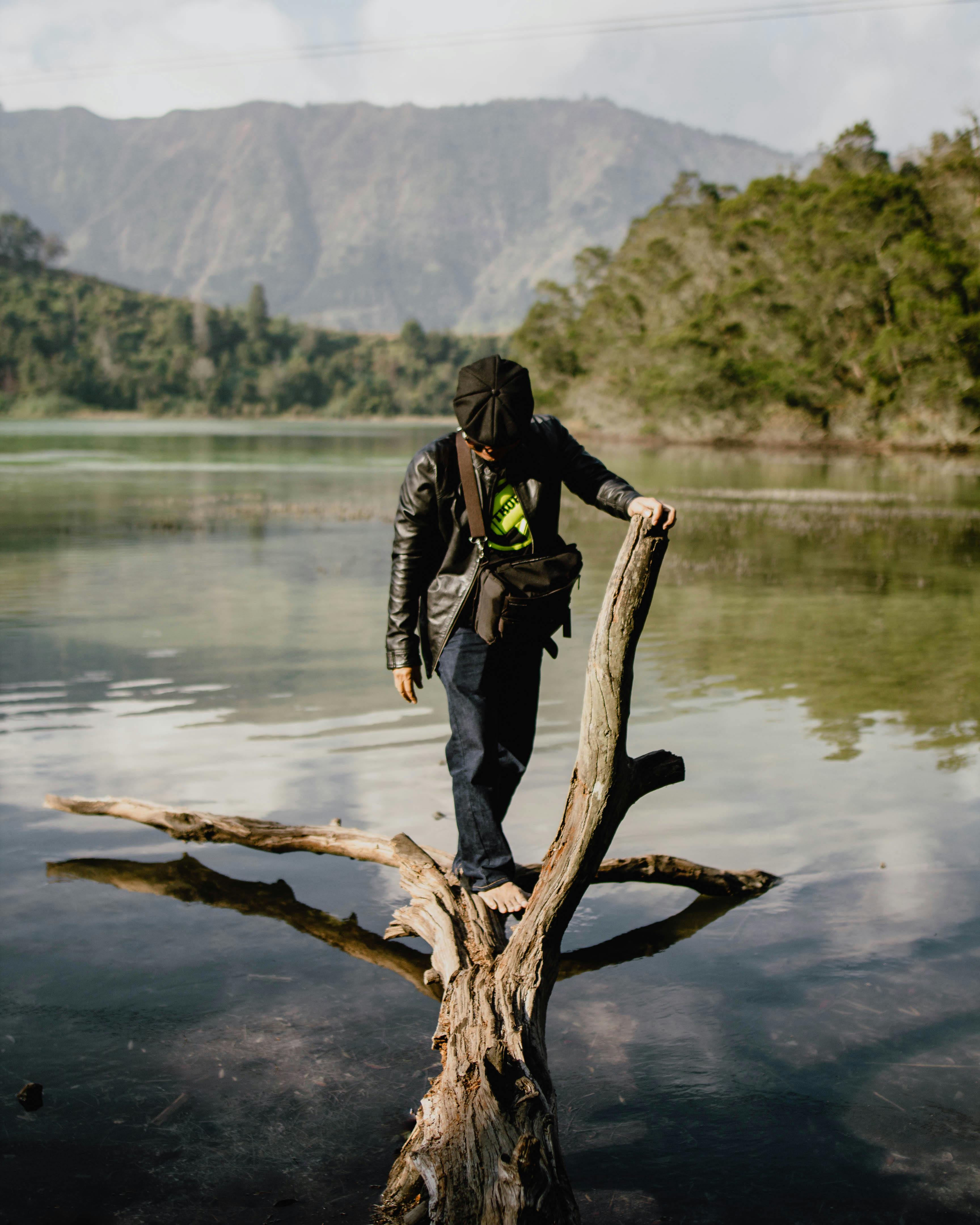 在印度尼西亚中爪哇省风景秀丽的湖泊中，一名男子在浮木上保持平衡，展现出宁静的冒险体验
