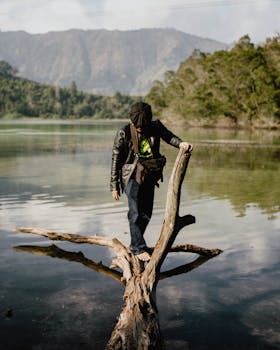 在印度尼西亚中爪哇省风景秀丽的湖泊中，一名男子在浮木上保持平衡，展现出宁静的冒险体验