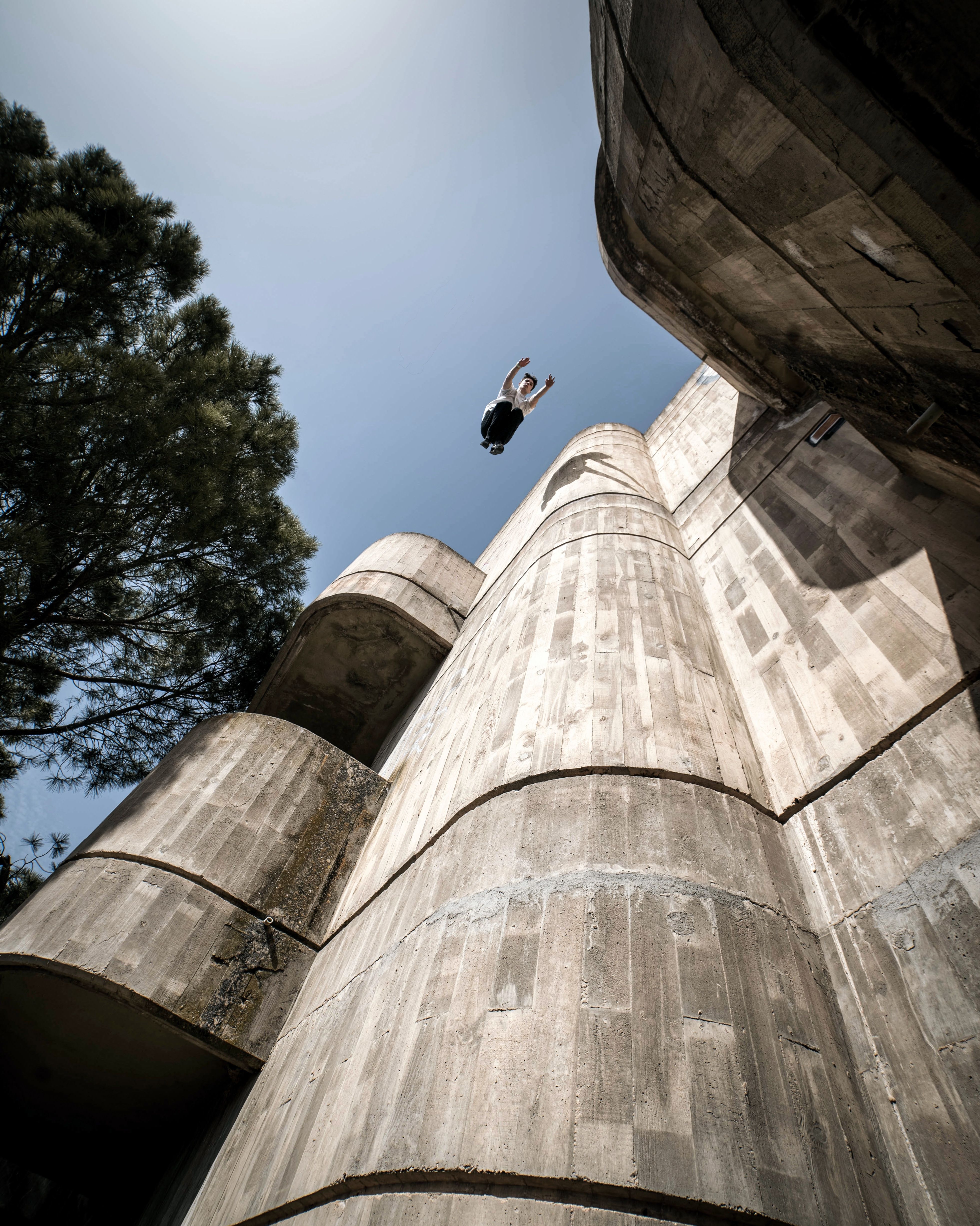 Young Man Jumping Out of a Tall Stone Building · Free Stock Photo