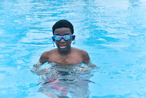 Free A young boy happily swimming in a bright turquoise pool, enjoying a sunny day. Stock Photo