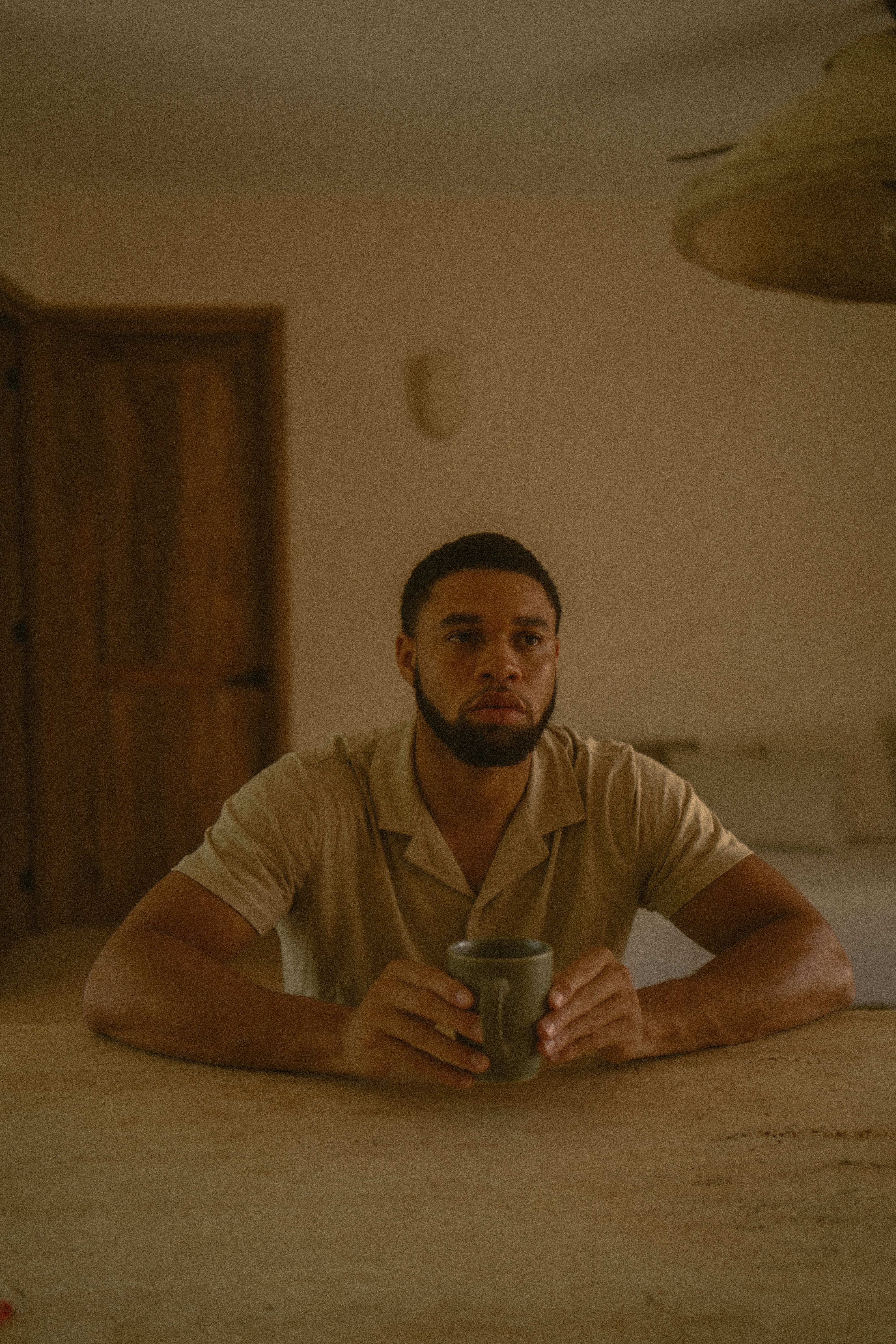Portrait of a man holding a coffee cup in a cozy indoor setting, reflecting in thought.