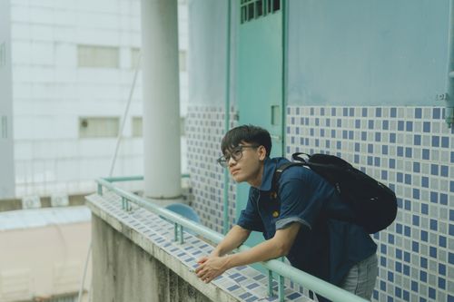 Free A young man leans on a balcony railing in Ho Chi Minh City, Vietnam. Stock Photo