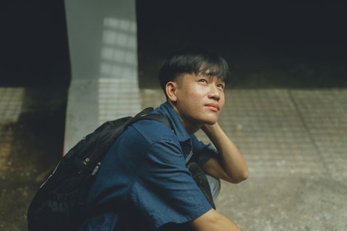 Free A young man sitting outdoors thoughtfully in Ho Chi Minh City, Vietnam. Stock Photo