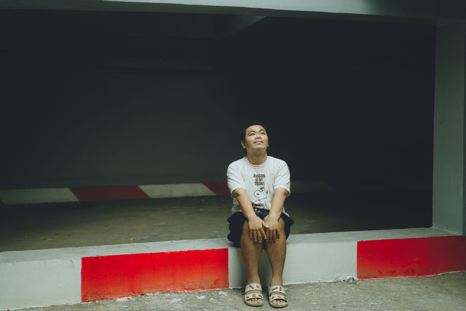 A man sitting thoughtfully in an urban parking area, serene expression.