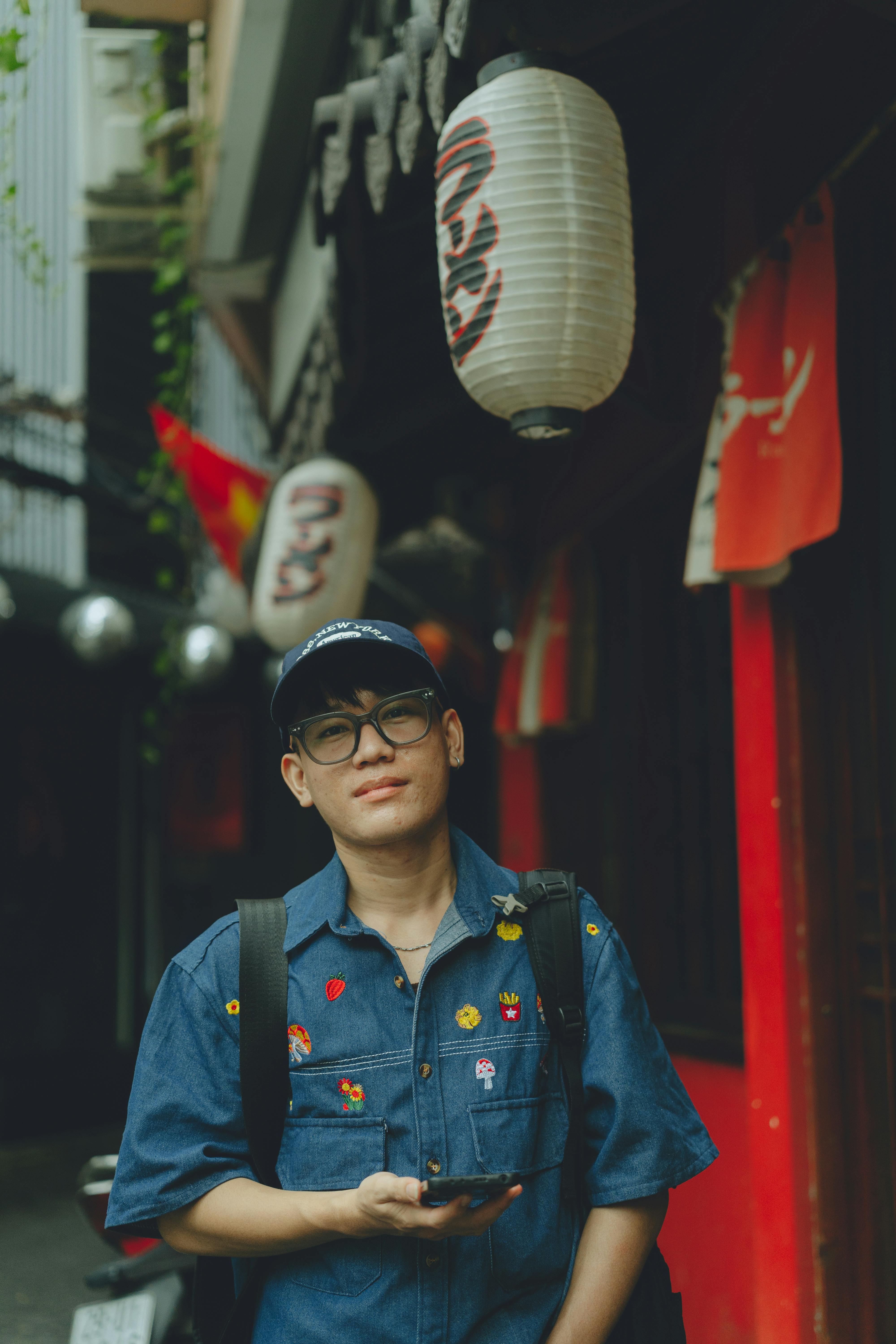 a man in a blue shirt and glasses standing in front of a building