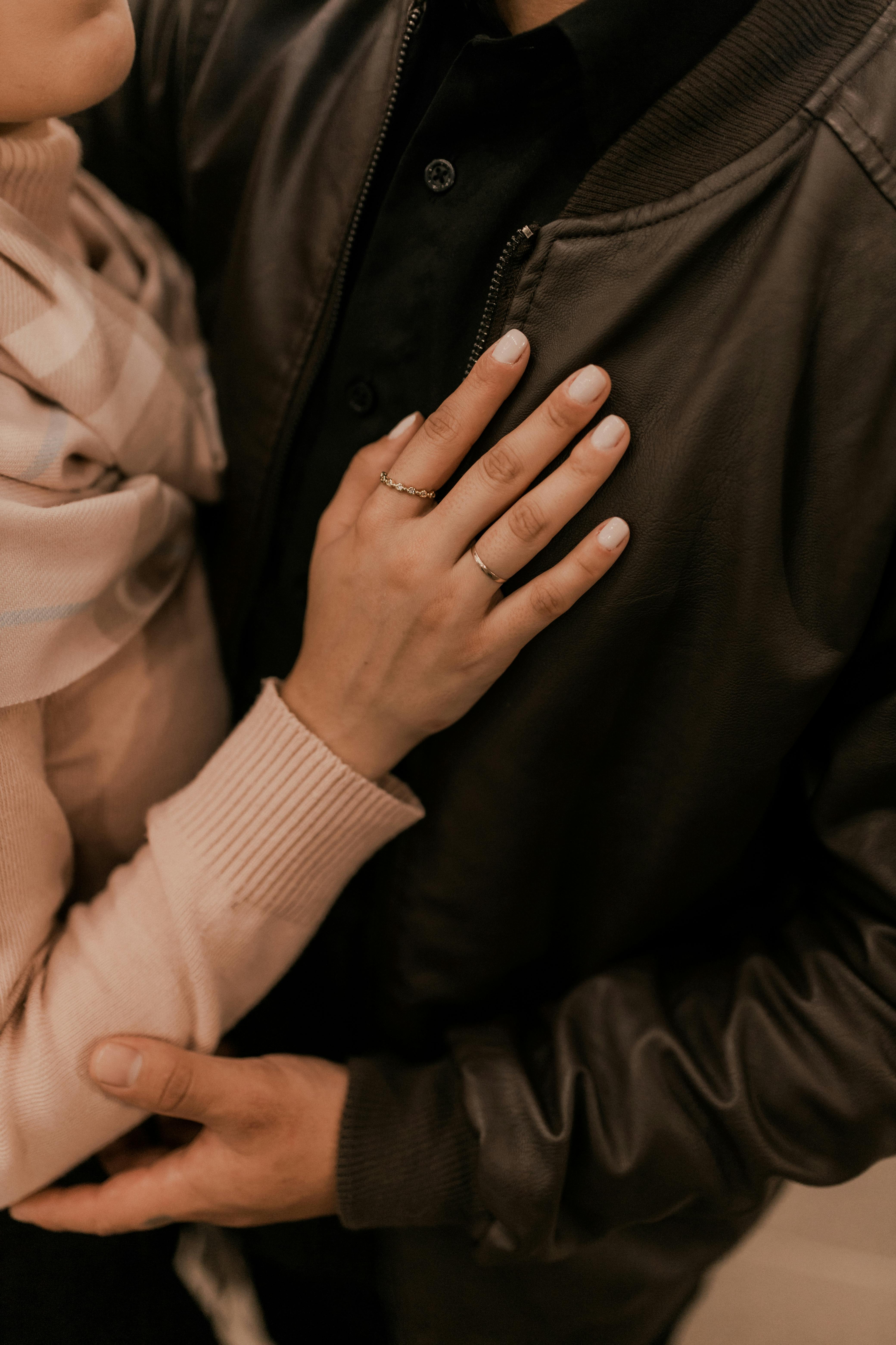 a man and woman hugging each other in a black jacket