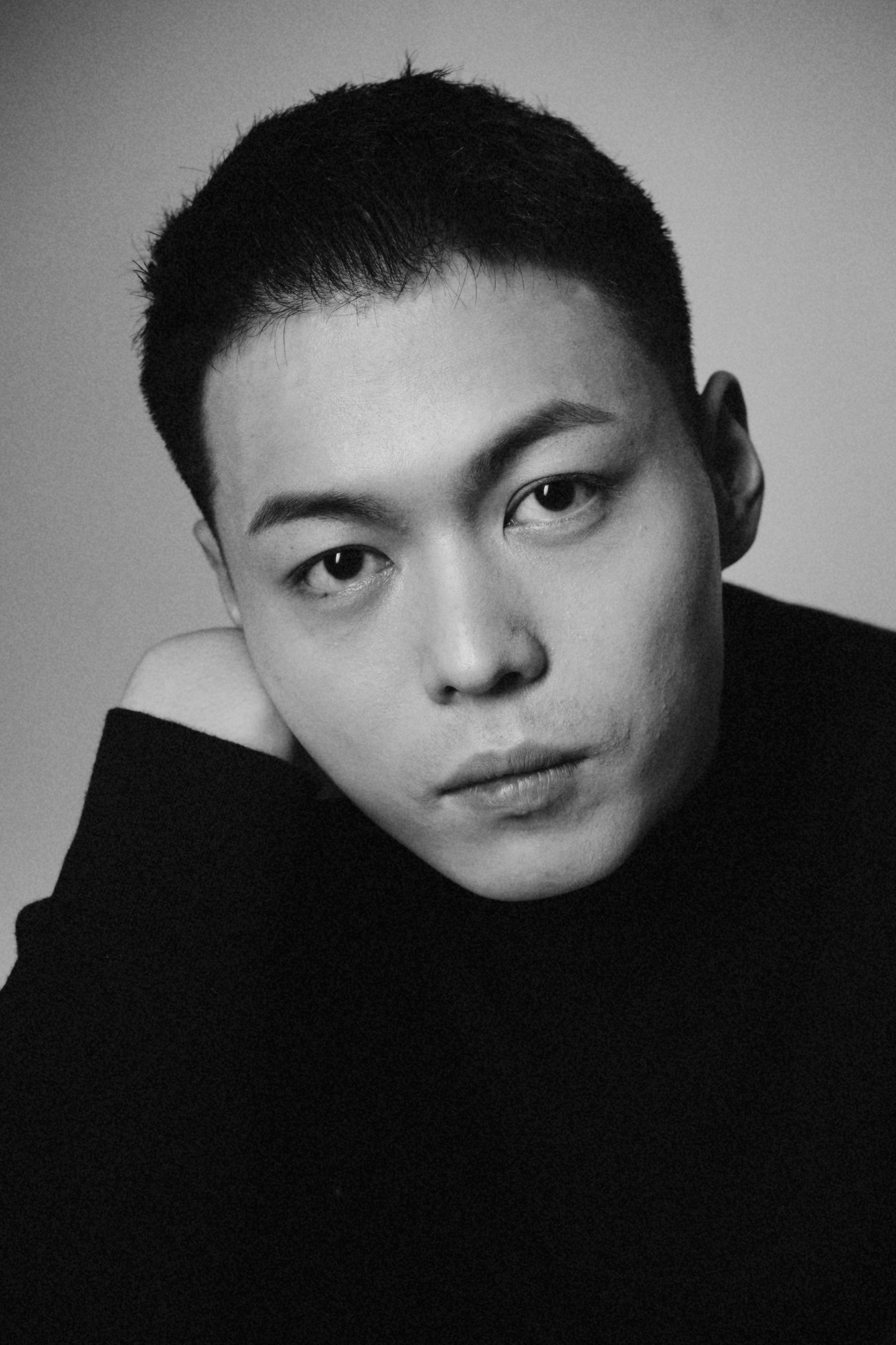 Artistic black and white portrait of a young man in a turtleneck sweater.