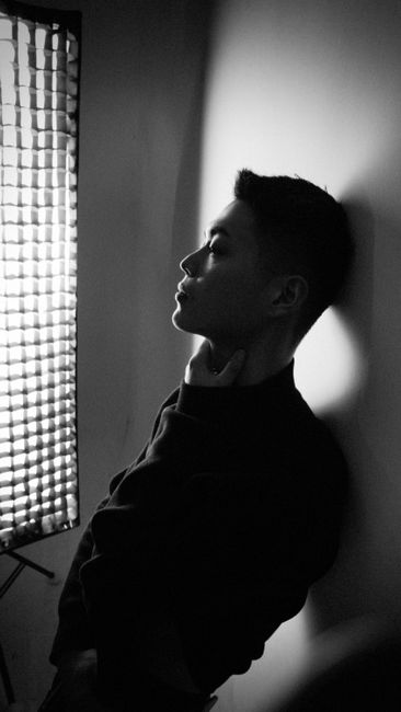 A striking black and white portrait capturing the pensive silhouette of a man by a window.