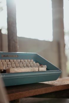 A vintage blue typewriter placed on a wooden desk with soft natural lighting.