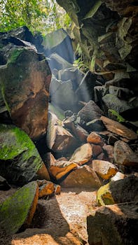 Sunlight beams through a rocky forest cave in La Libertad, El Salvador.
