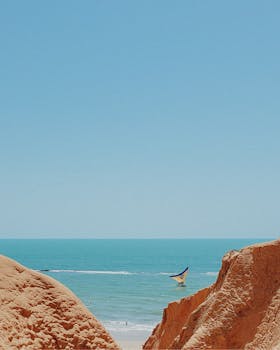 Explore the stunning coastal landscape of Canoa Quebrada, Brazil with vibrant cliffs and blue ocean waters.