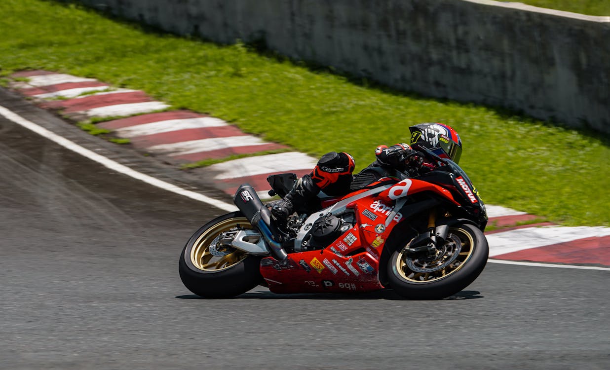 A motorcycle racer is riding down a track · Free Stock Photo