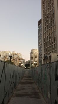 Cityscape with tall buildings and graffiti-covered walls at dusk, a blend of urban art and architecture.
