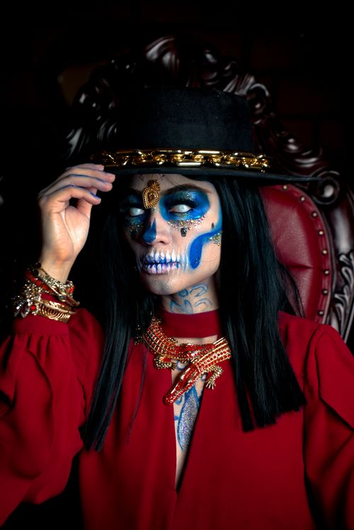Free Striking portrait of a woman in traditional Dia de los Muertos makeup with a red costume and ornate accessories. Stock Photo