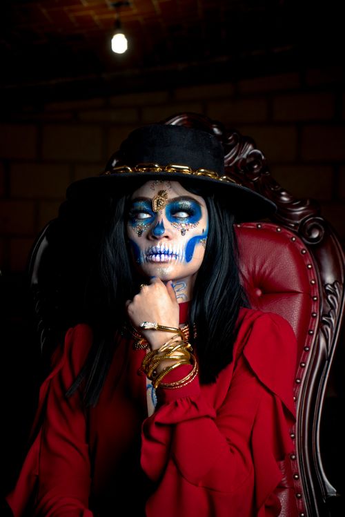 Free A woman in vibrant Dia de los Muertos makeup sits elegantly in an armchair. Stock Photo