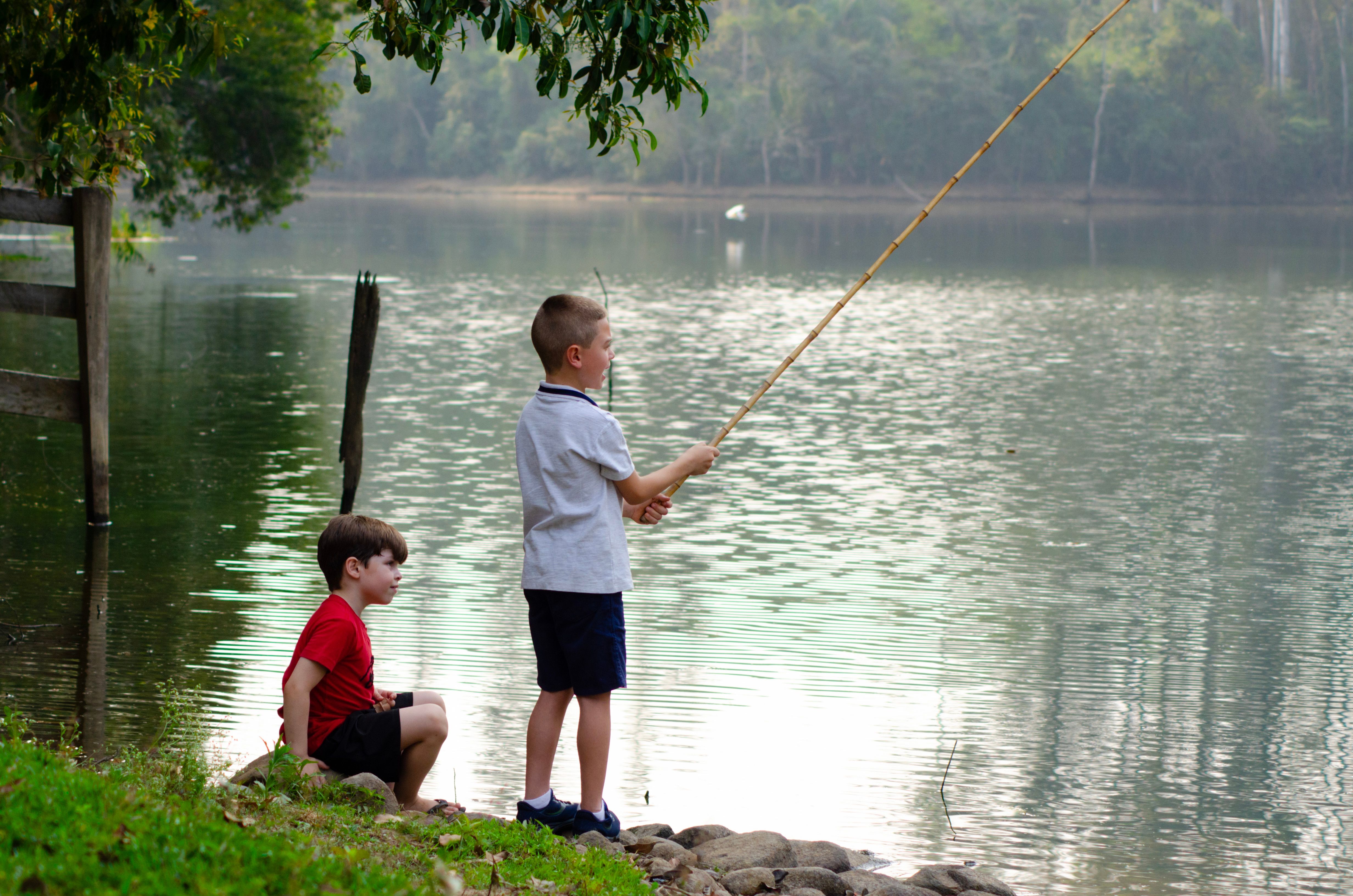 Two children enjoy fishing by a tranquil riverside in Porto Feliz, Brazil.